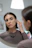 Photo of a woman admiring her elegant earrings in front of a mirror with natural light.