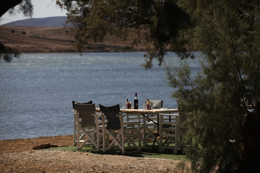 a couple of chairs sitting at a table next to a body of water