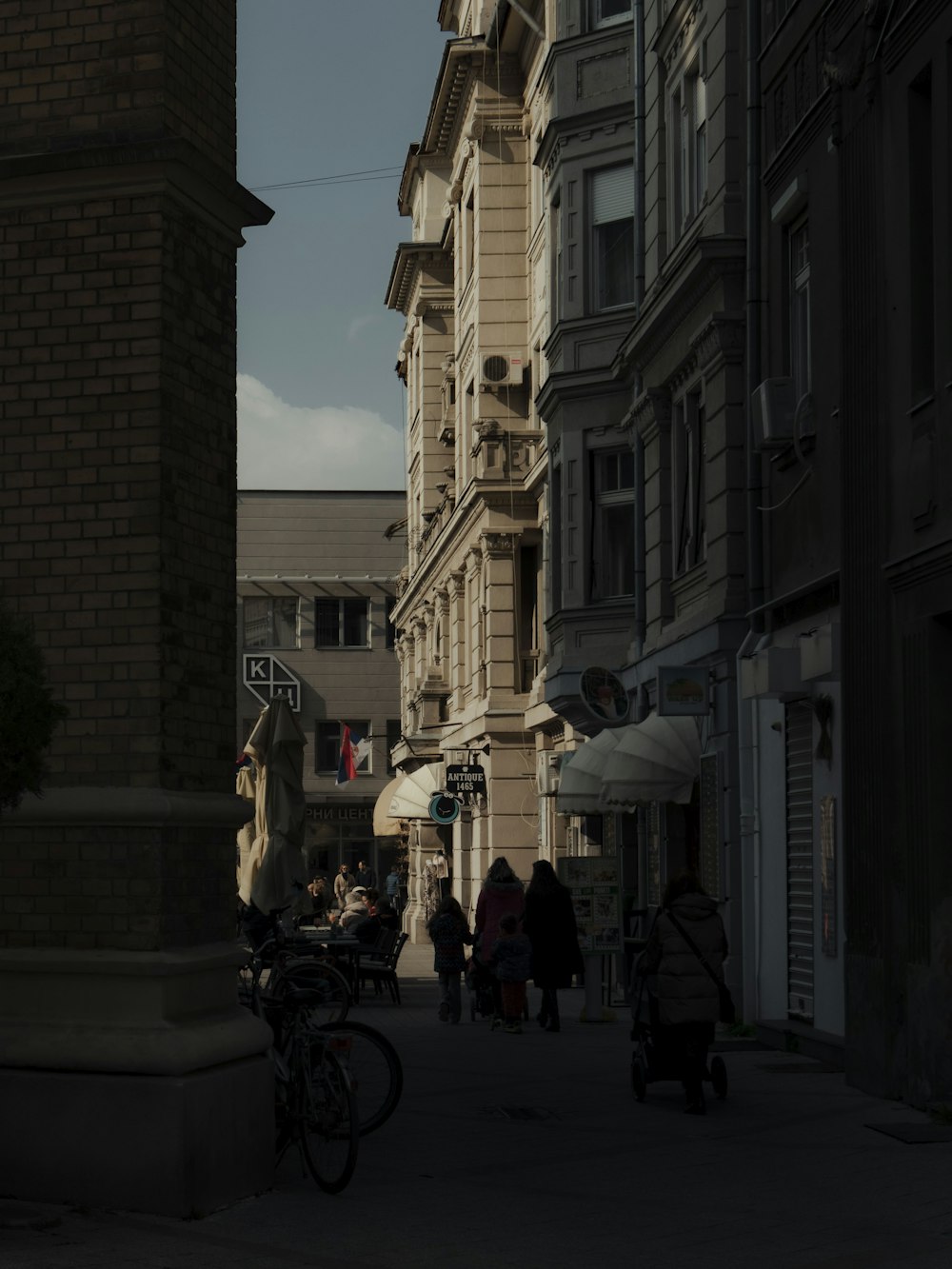 a group of people walking down a street next to tall buildings