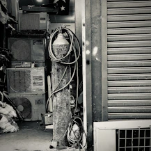 Technician repairing an air conditioner unit with tools in a residential setting.