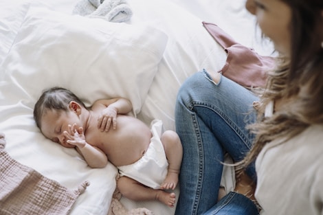 a baby laying on a bed next to a woman