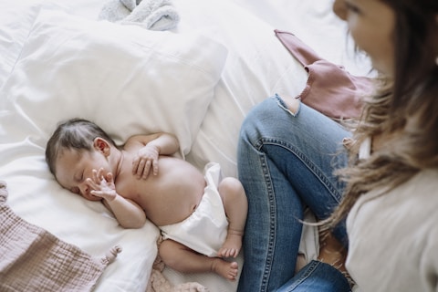 a baby laying on a bed next to a woman