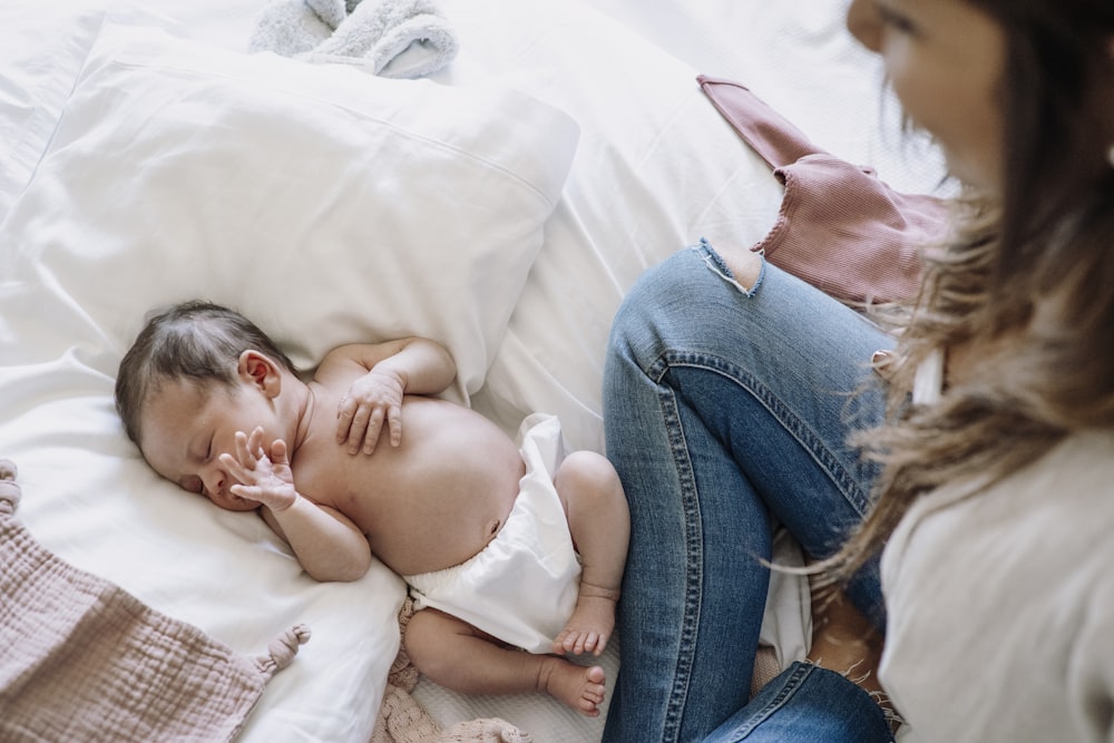 a baby laying on a bed next to a woman