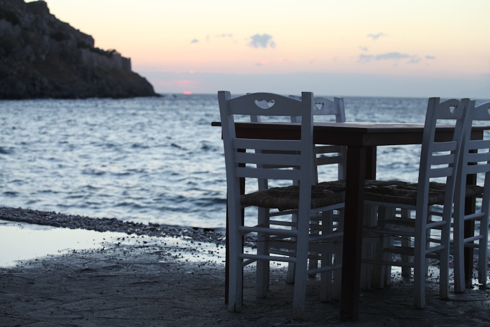 a table and chairs sitting on a beach near the ocean