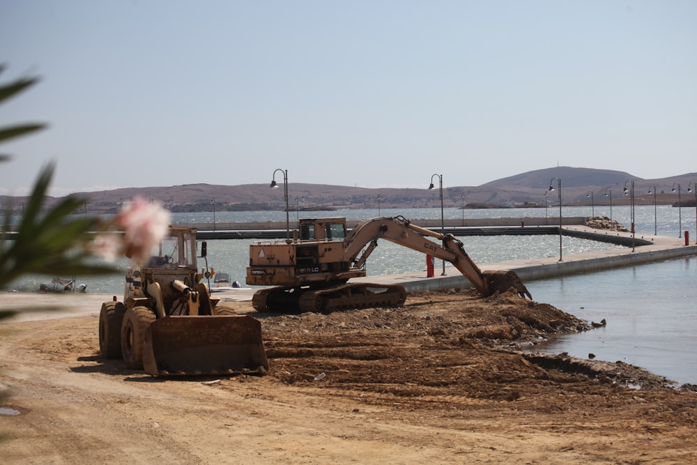 a bulldozer is parked on a beach next to a body of water