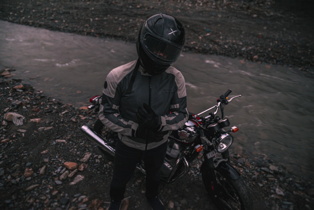 a person sitting on a motorcycle next to a river