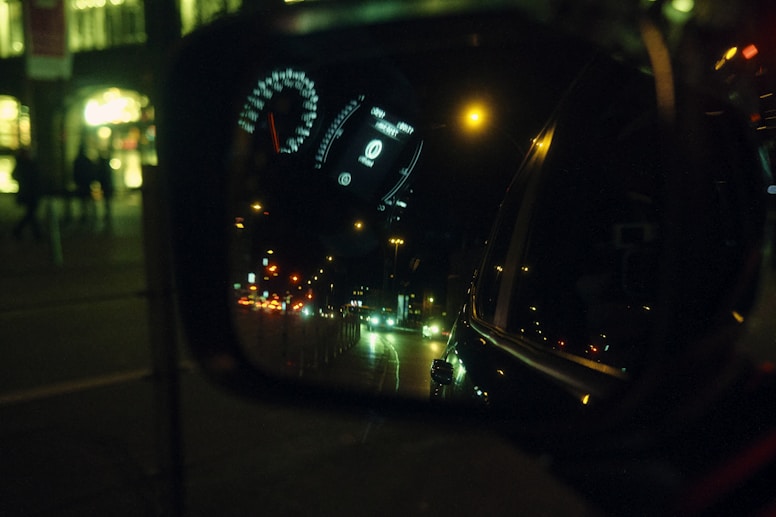 a rear view mirror reflecting a city street at night