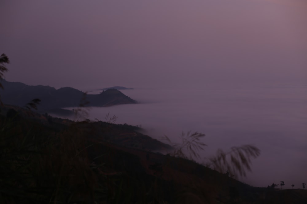 a view of a foggy mountain at dusk