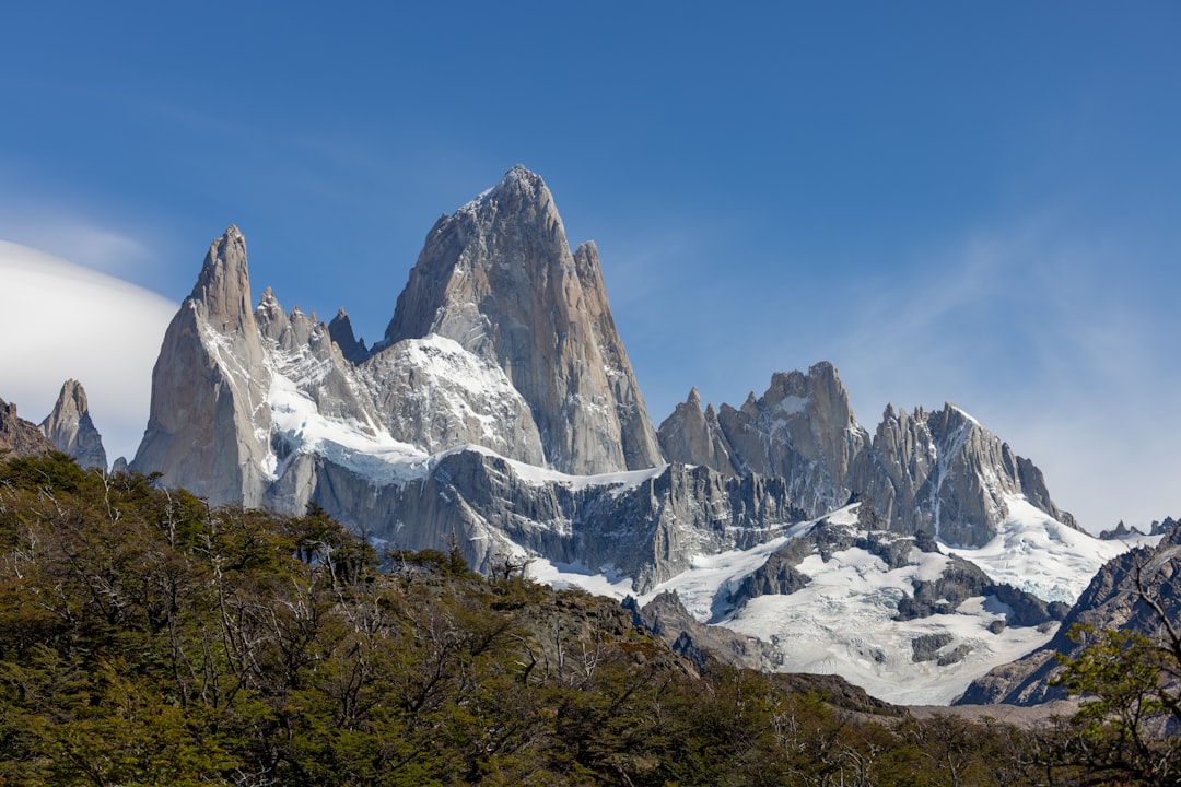 a mountain range covered in snow and surrounded by trees,