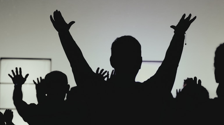 A sunset silhouette of people raising candles in peaceful solidarity.