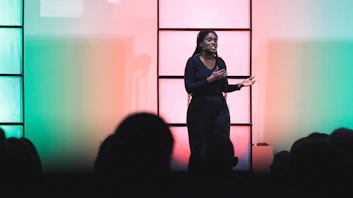 A confident speaker engaging an audience with expressive hand gestures on stage.