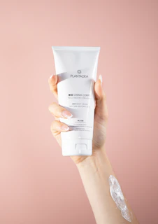 Hands applying a rosálume moisturizer, highlighting the creamy texture and delicate packaging.