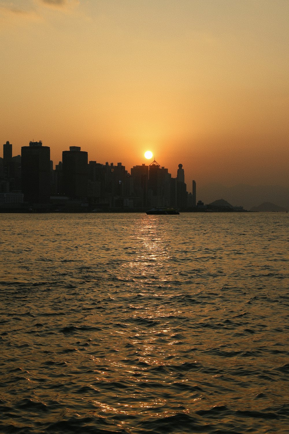 the sun is setting over a city on the water