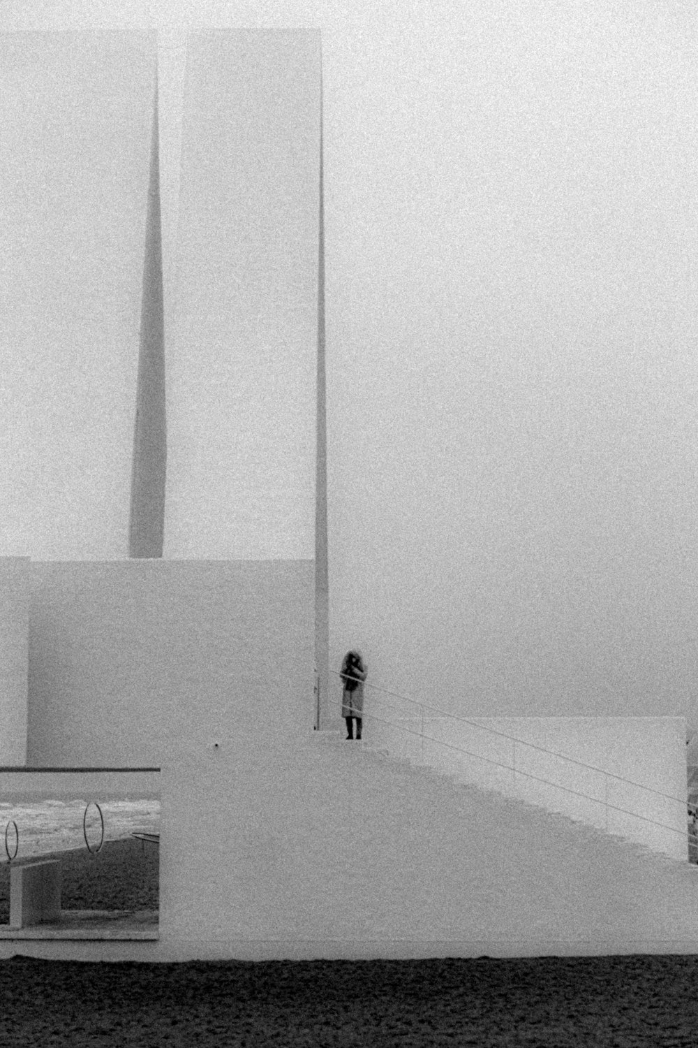a black and white photo of a person standing on a building