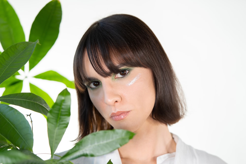 a woman standing next to a green plant