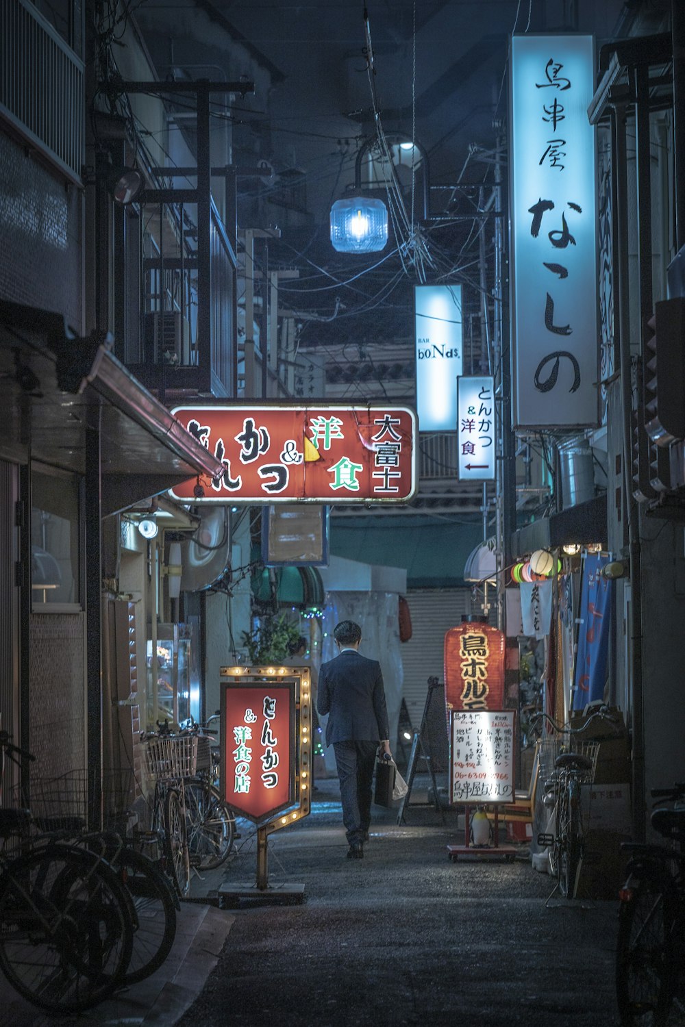 a man walking down a narrow alley way at night