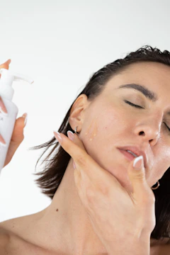 a woman is applying a lotion on her face