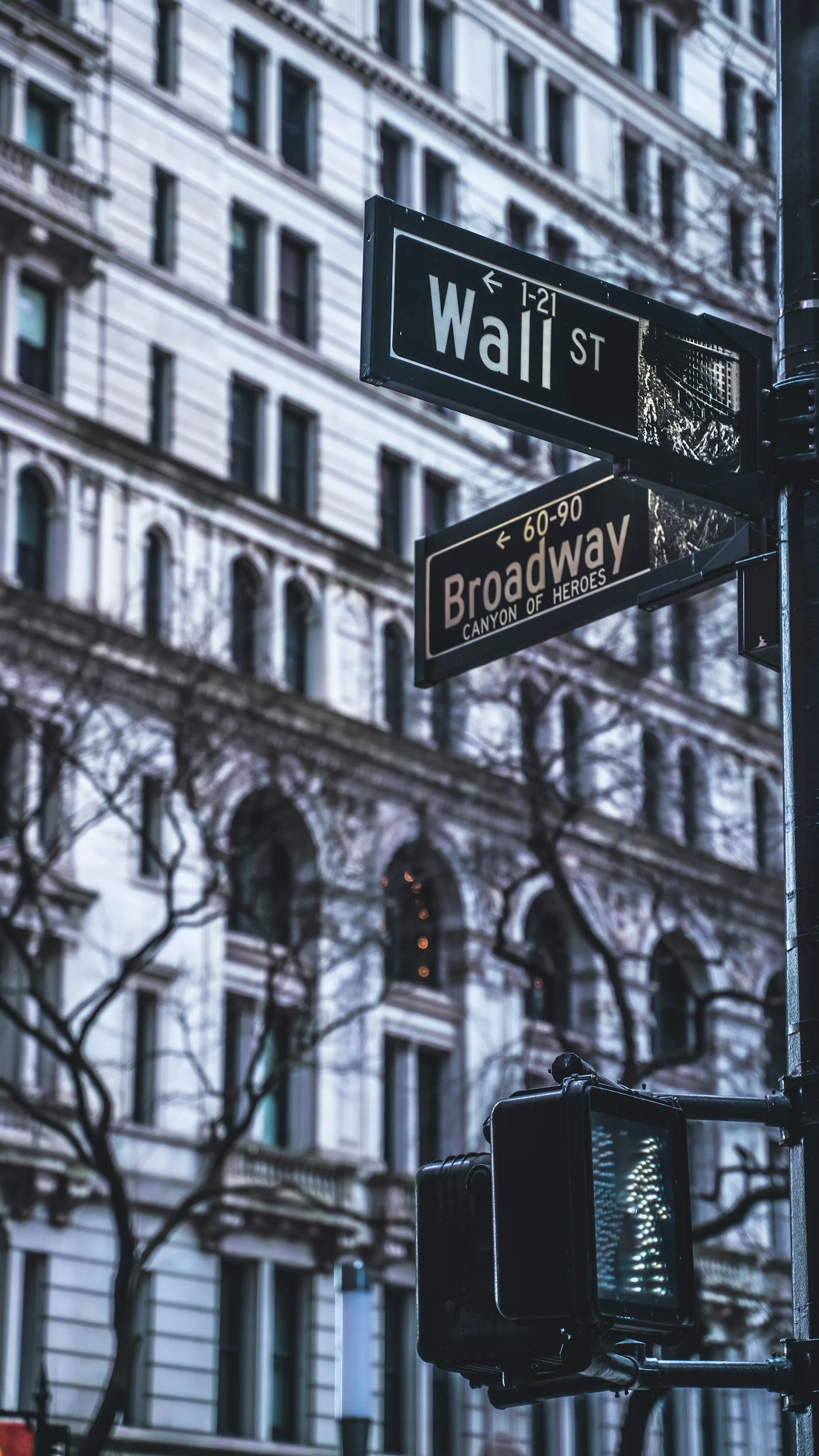 A Wall Street sign and traffic light in front of a building in New York