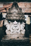 a statue of a person sitting on top of a stone pillar