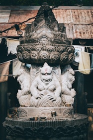 a statue of a person sitting on top of a stone pillar
