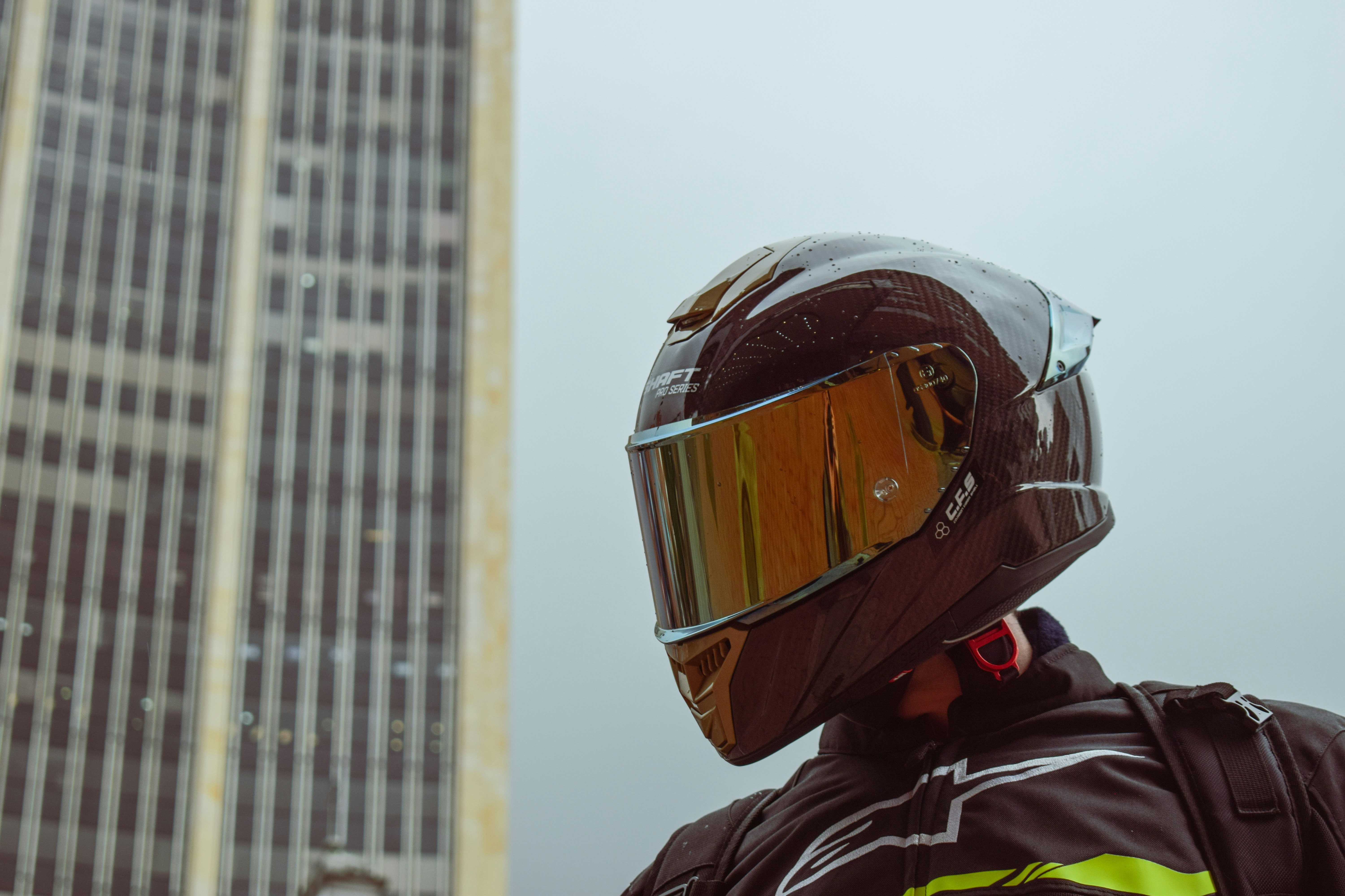 a man wearing a motorcycle helmet standing in front of a tall building