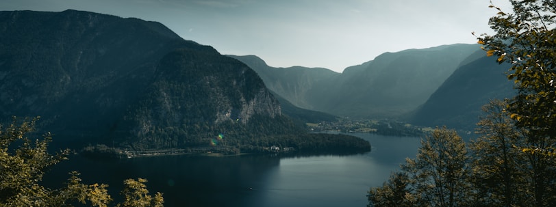 A serene landscape with a calm lake surrounded by mountains and trees, representing tranquility and wellness.