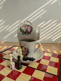 A collection of classic board games stacked beside a steaming cup of tea.