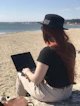 A digital nomad working on a laptop from a beach.