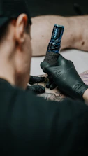 Close-up of a tattoo machine delicately inking a detailed sacred geometry tattoo on the arm.