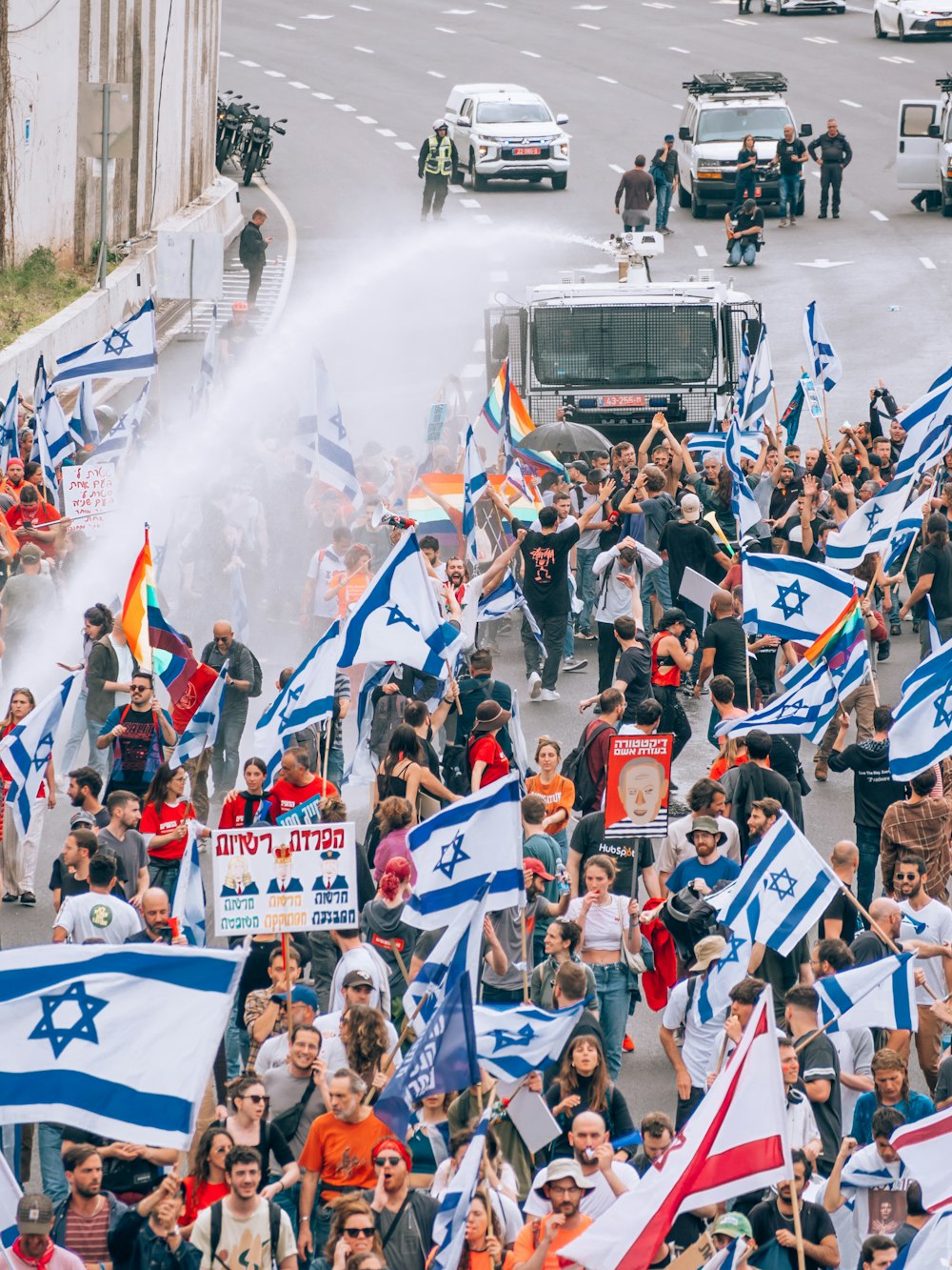 a large group of people holding flags and spraying water