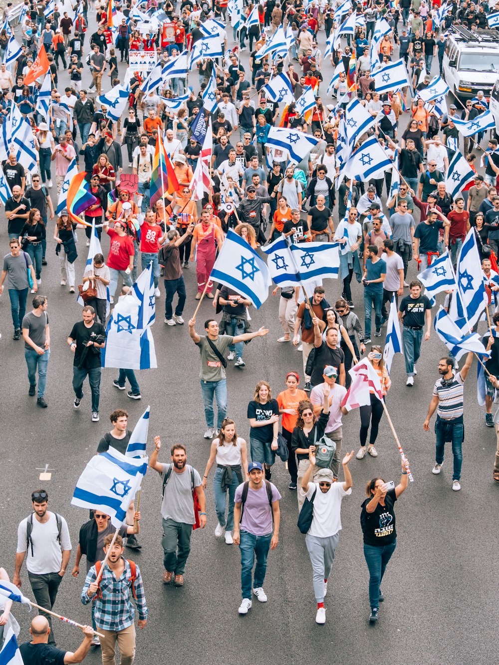 a large group of people walking down a street holding flags