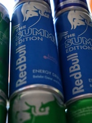 Several cans of energy drink with a prominent branding design. The cans feature a blue and green color scheme, with the phrase 'The Summer Edition' highlighted on the label.