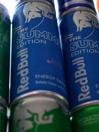 Several cans of energy drink with a prominent branding design. The cans feature a blue and green color scheme, with the phrase 'The Summer Edition' highlighted on the label.