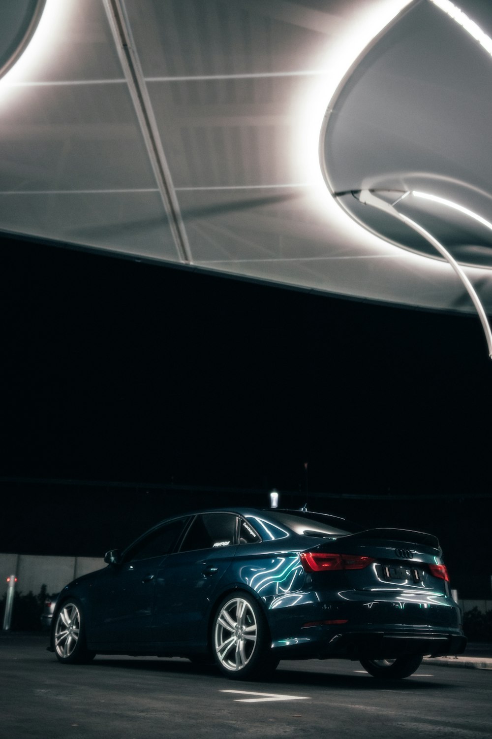 a blue car parked in a parking lot at night