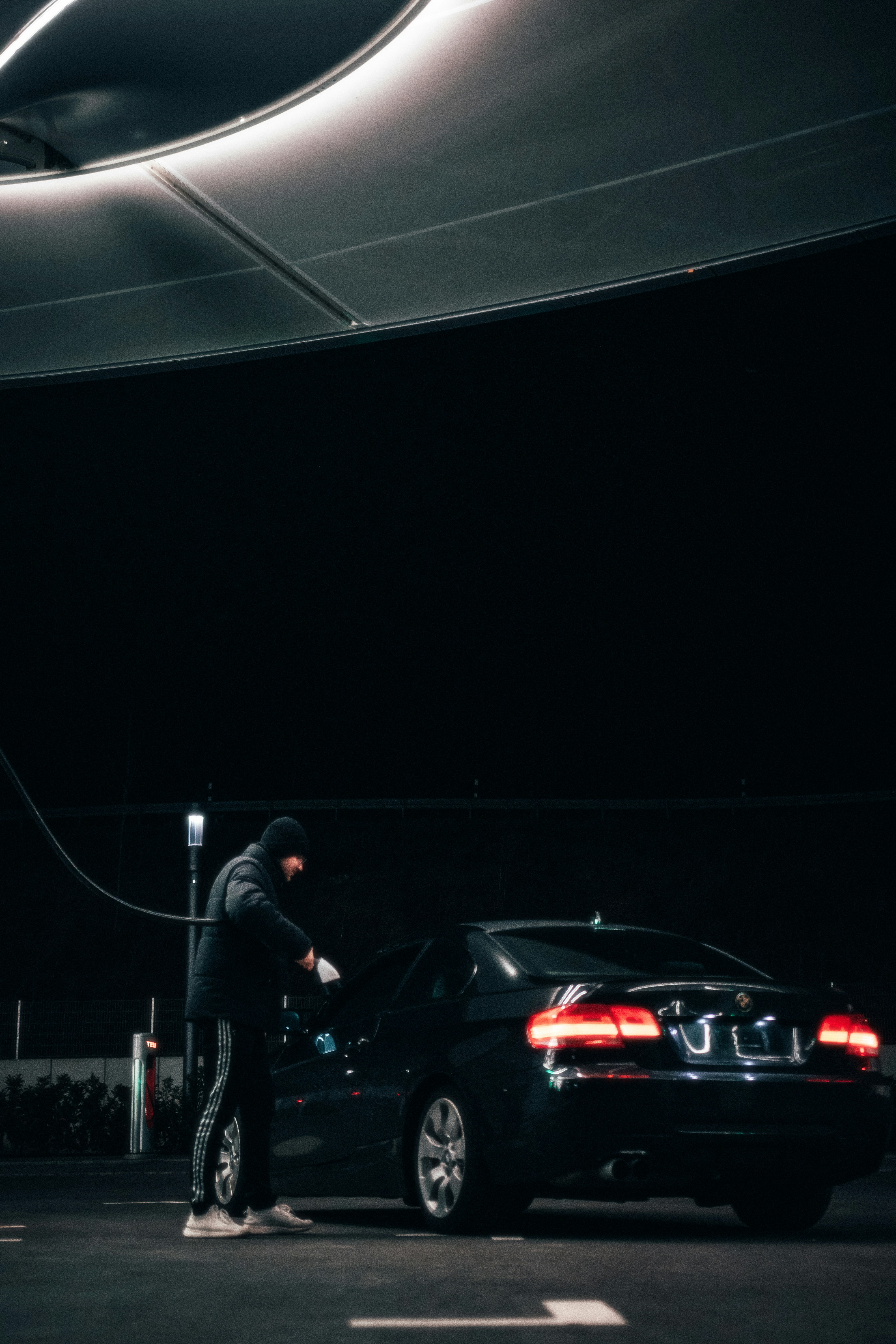 a man standing next to a black car in a parking lot