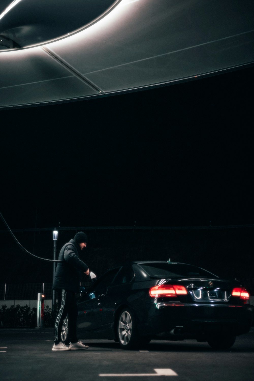 a man standing next to a black car in a parking lot