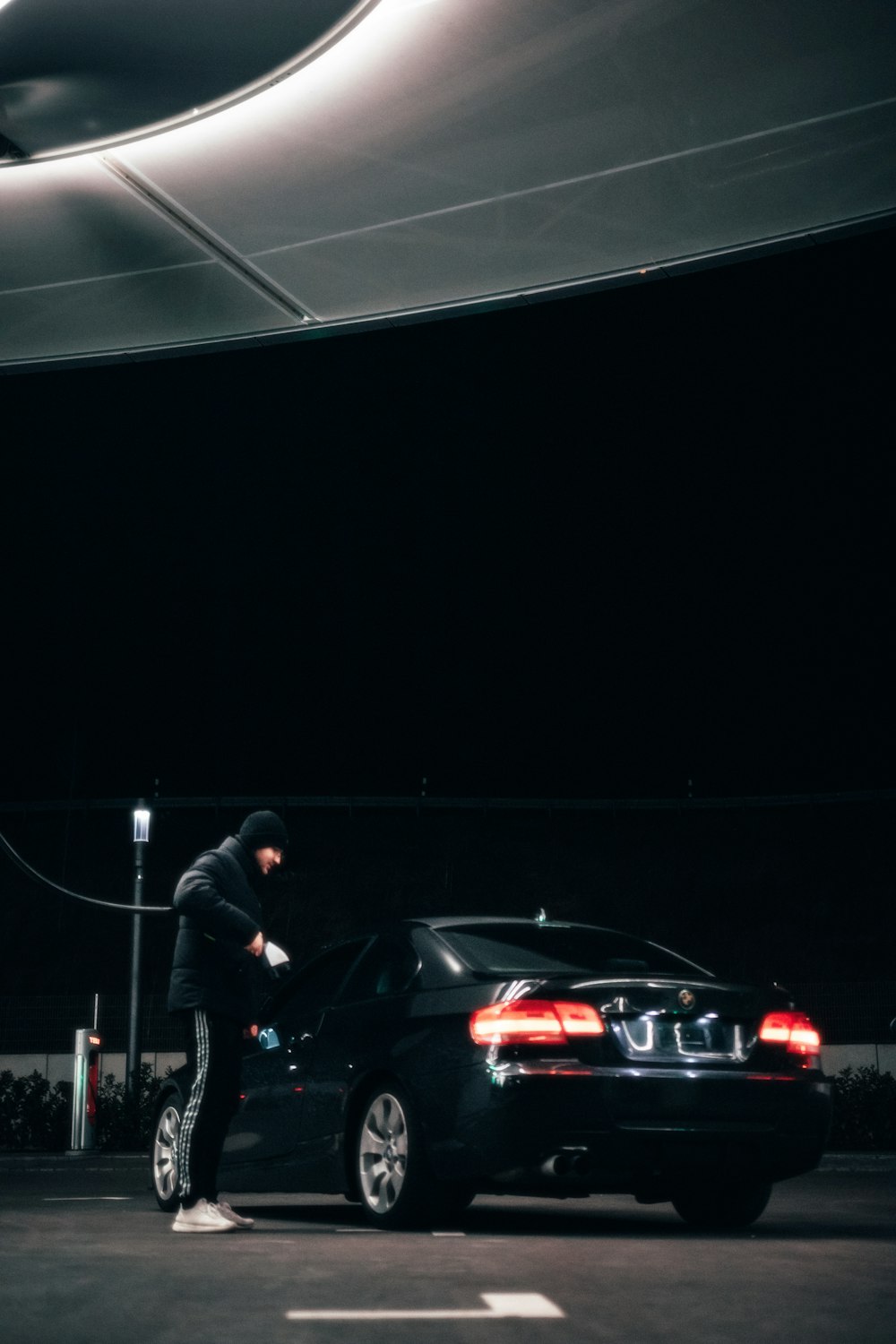 a man standing next to a black car in a parking lot