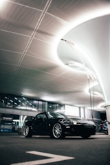 A sleek black sports car with a custom matte finish parked under soft lighting.