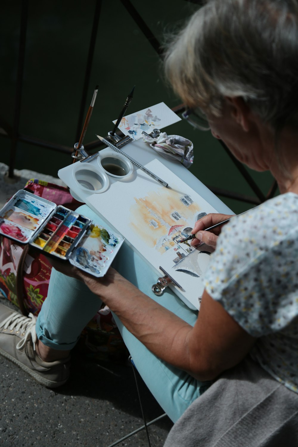 a woman sitting at a table working on a painting