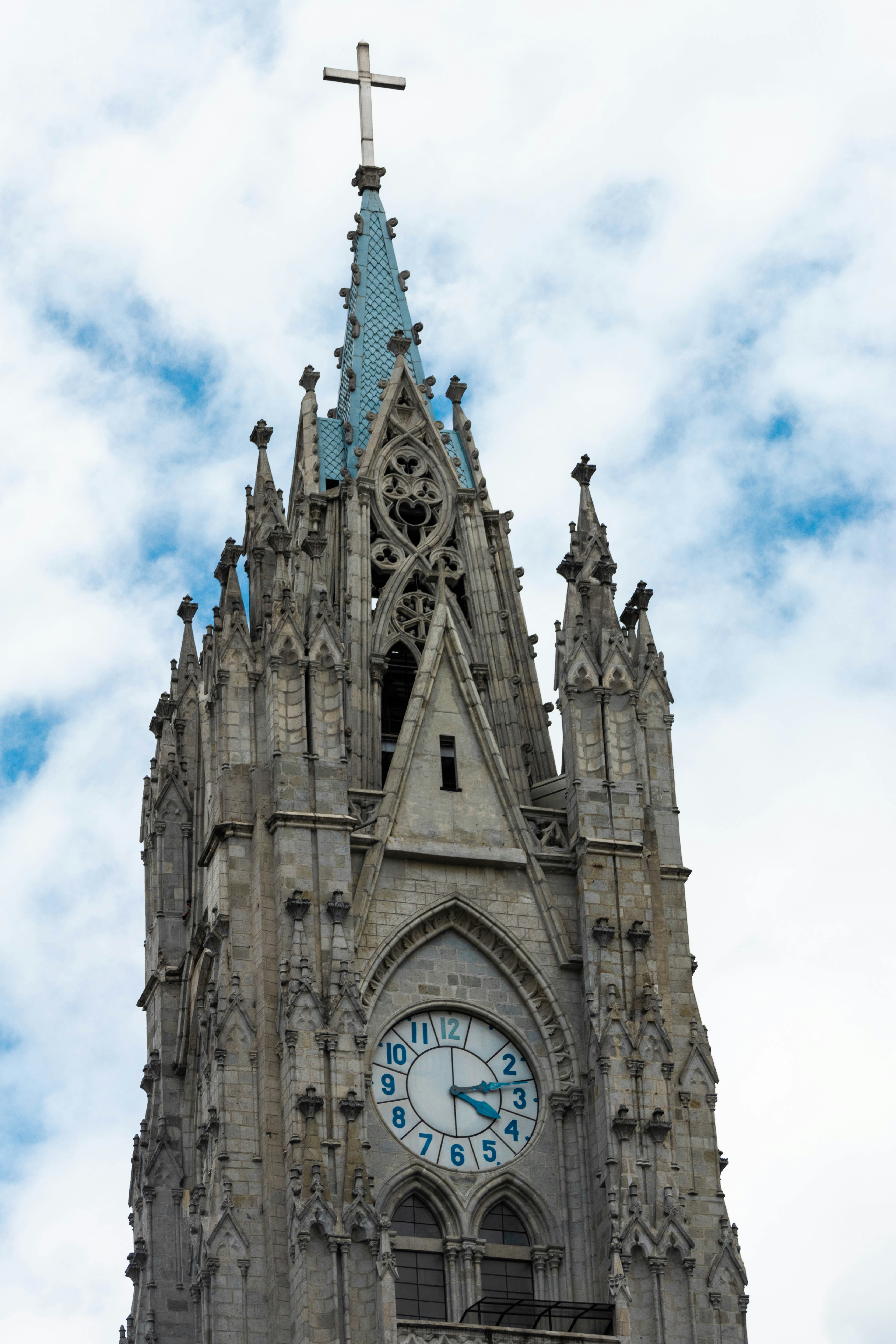 a very tall clock tower with a cross on top
