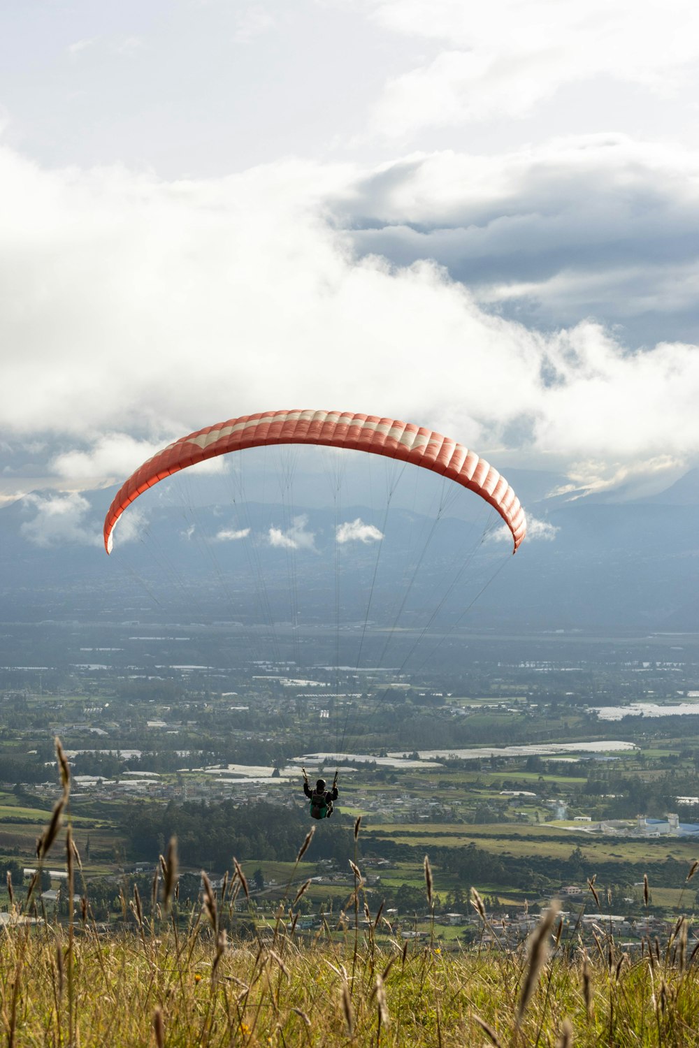 a person paragliding over a lush green field
