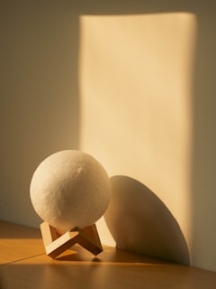 a white ball sitting on top of a wooden stand