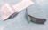 An opened adhesive bandage is lying on a light blue surface. The bandage is partially unwrapped, revealing a white pad on one side. The wrapper features text and branding details. Next to the bandage is the paper backing that has been removed.