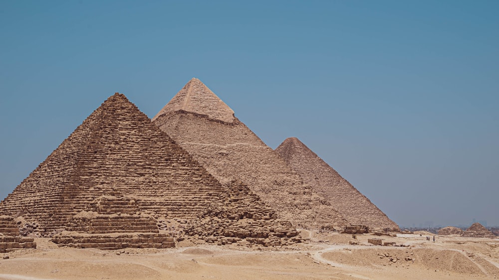 three pyramids in the desert with a blue sky in the background