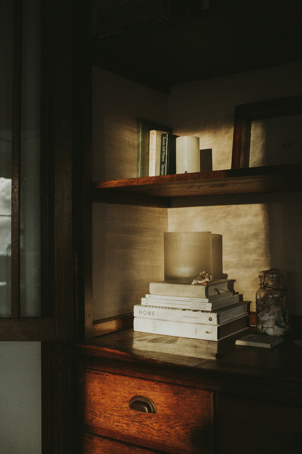 a stack of books sitting on top of a wooden dresser