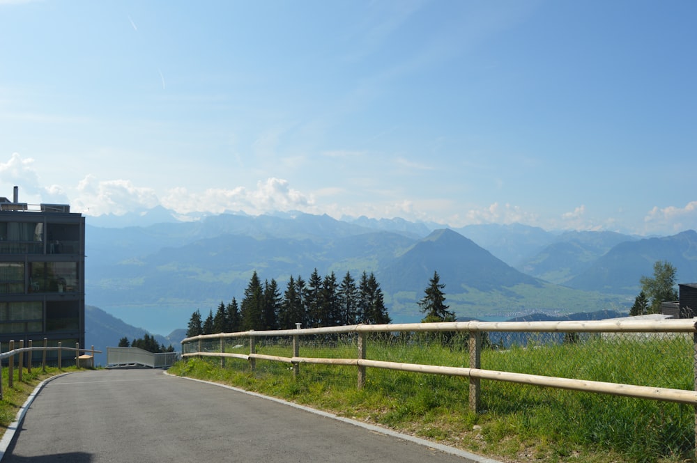 a road with a fence on the side and mountains in the background