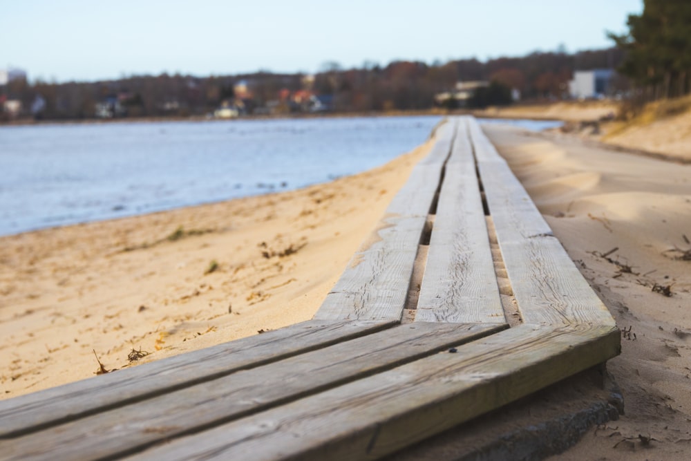 a wooden bench sitting on top of a sandy beach