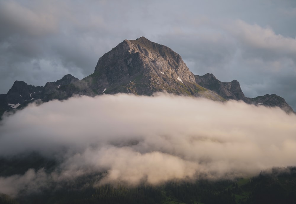 a large mountain covered in clouds under a cloudy sky