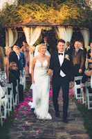 Guests smiling and clapping as the couple walks down the aisle together.