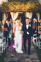 An officiant warmly smiling as a couple exchanges vows in an intimate outdoor setting.